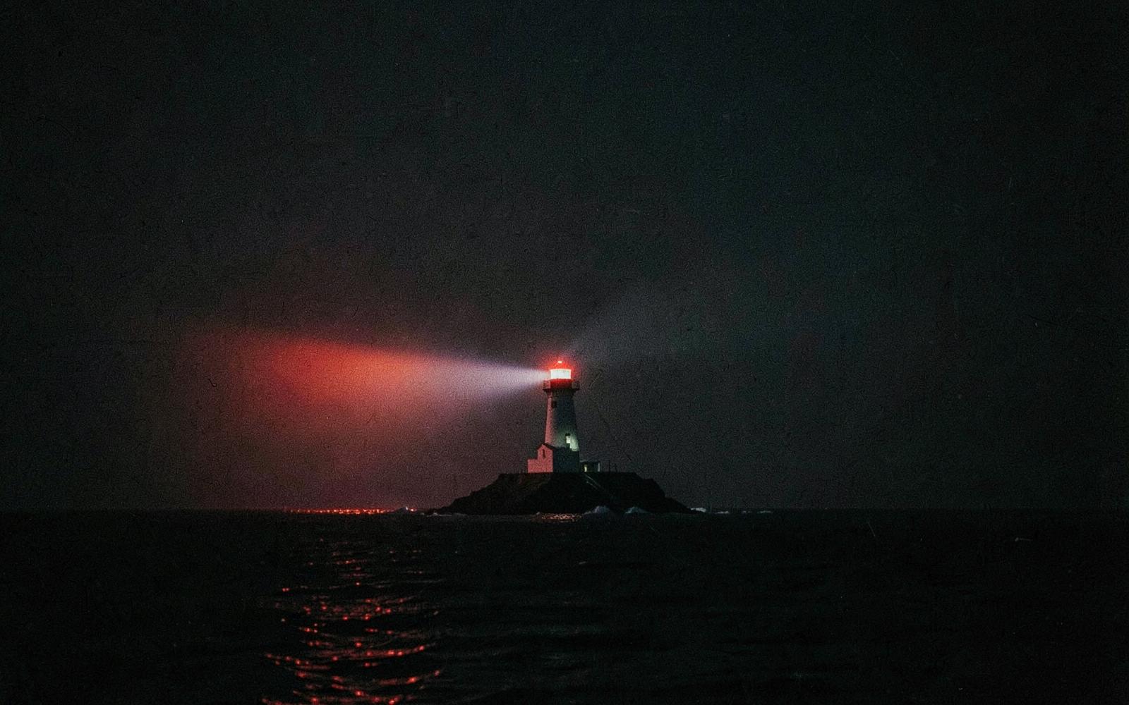 A lighthouse beam cutting across dark water at night